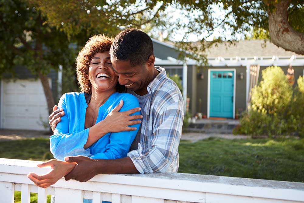 Man hugging woman in front of house